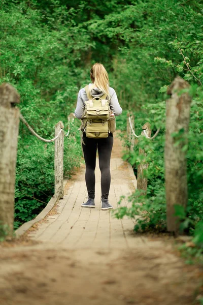 Mujer excursionista en puente forestal — Foto de Stock