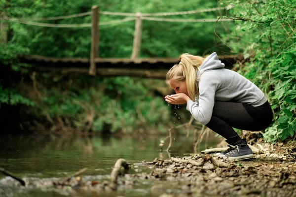 Mulher bebendo uma corrente de água doce — Fotografia de Stock