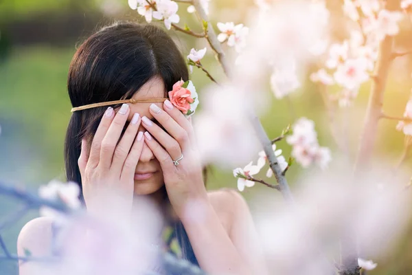 Mujer joven cubrir los ojos árbol de flores — Foto de Stock