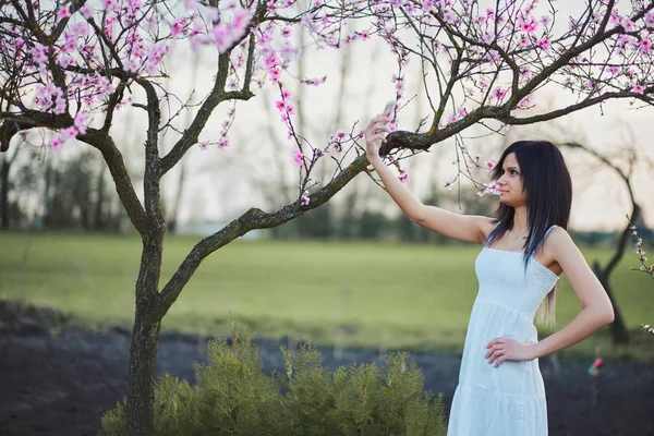 Žena s květy stromu foto s mobilním telefonem — Stock fotografie