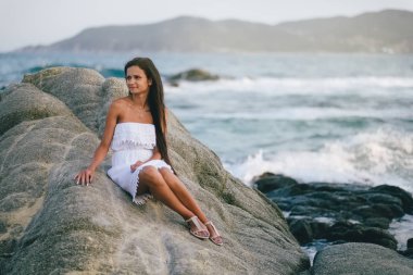 Deniz kıyısında bir kaya üzerinde oturan kadın