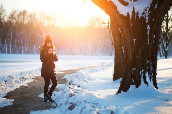 Mujer sosteniendo té caliente en invierno nevado parque — Foto de Stock