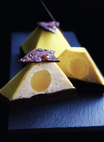 Postres de pirámide con textura amarilla en rodajas en brownie con choc oscuro — Foto de Stock