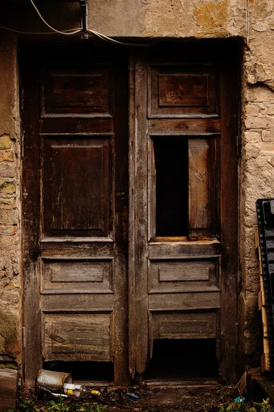 Velha porta marrom de madeira quebrada com garrafas vazias no chão — Fotografia de Stock