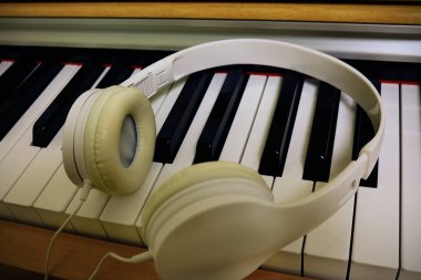 Piyano açık sarı ahşap klavye ve kulaklık.