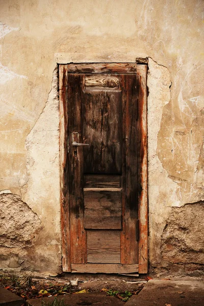 Velha porta marrom de madeira quebrada com alça alta sobre o solo — Fotografia de Stock