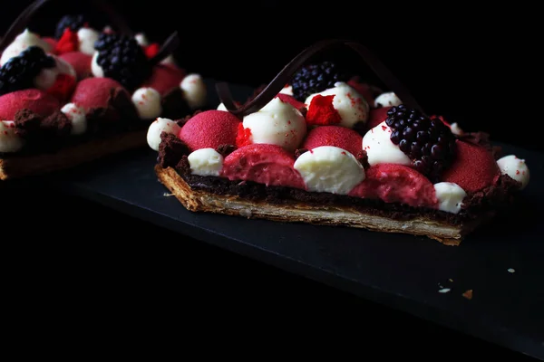 Desserts en mousse de groseille rouge et pâte feuilletée aux mûres avec ganache fouettée et décorations en spirale au chocolat, section — Photo