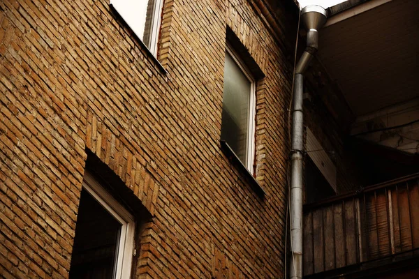 Stängda fönster i tegelvägg med avlopp och balkong — Stockfoto