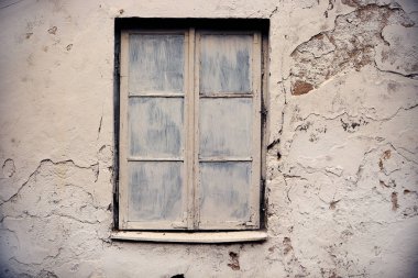 Eski beyaz pencereli eski beyaz duvarda çatlaklar var.