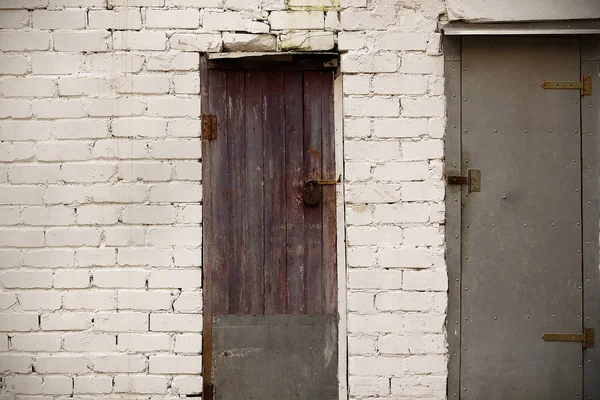 Due diverse vecchie porte rotte con lucchetti chiusi in muro di mattoni bianchi — Foto Stock