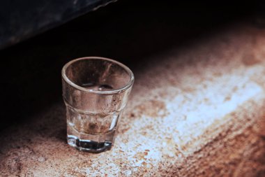 Beton yüzeyde tek başına duran küçük boş bir bardak.