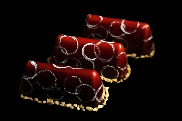 チョコレートミラー釉薬ピーナッツとシルバーサークルの装飾と3つのチョコレートファンシーデザートの行 — ストック写真