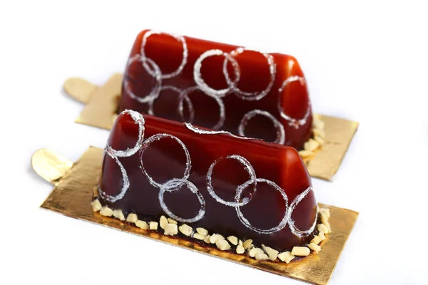 Two chocolate fancy desserts with chocolate mirror glaze peanuts and silver circles decoration