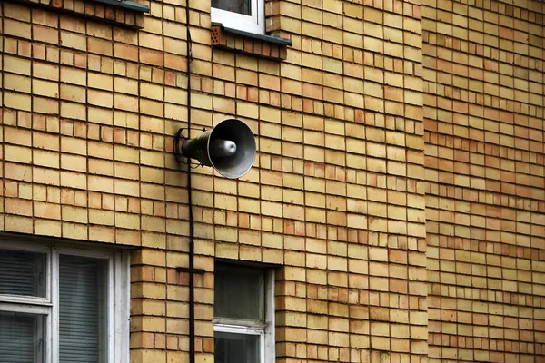 Ancien haut-parleur de corne accroché au mur de construction en brique jaune — Photo