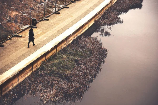 Женщина, идущая вдоль берега реки с ростом воды — стоковое фото