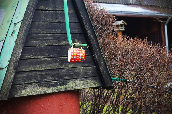 Cute heart design cup hanging on metal handle of country well — ストック写真