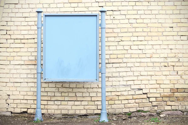 Metallo blu commerciale stand bordo vicino muro di mattoni gialli — Foto Stock