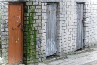 Kahverengi ve gri ahşap kapılar Islak beyaz tuğlalı duvarlar Yeşil yosunlu