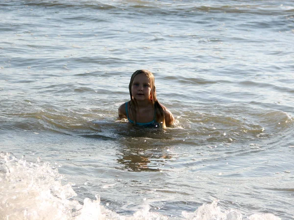 Klein meisje in de golven spelen — Stockfoto