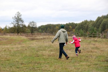 Bir alandaki kızıyla oynayan genç Baba