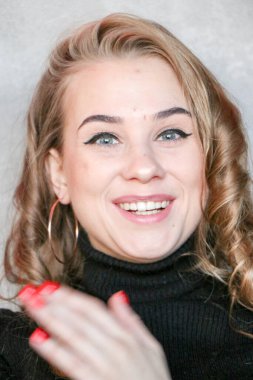 Uzun kıvırcık saçlı ve altın takılı güzel bir kadın. Bir kafede poz vermek, büyük küpeler, gülüşmeler, flörtler..