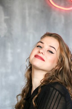 Uzun kıvırcık saçlı ve altın takılı güzel bir kadın. Bir kafede poz vermek, büyük küpeler, gülüşmeler, flörtler..