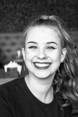 Siyah elbise giyen zarif sarışın kız bir kafede dinleniyor. Reklam, moda, ticari tasarım. Siyah elbiseli bir kız. Bir kafede güzel bir kız. Siyah ve Beyaz, Gülümseyen, Gülen, Kıvırcık Uzun Saçlı