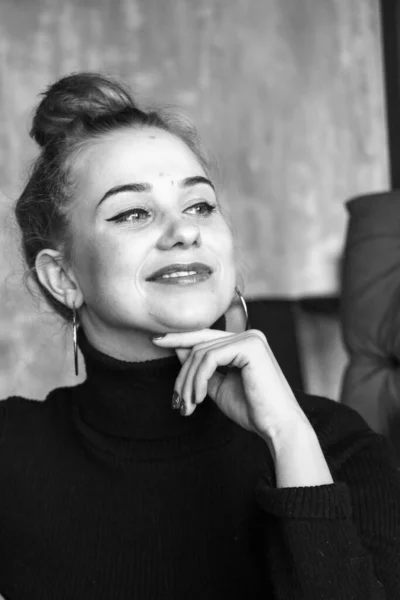 Menina loira elegante bonita vestindo um vestido preto é relaxante em um café. Publicidade, moda, design comercial.Menina em um café em um vestido preto. Menina bonita em um café . — Fotografia de Stock