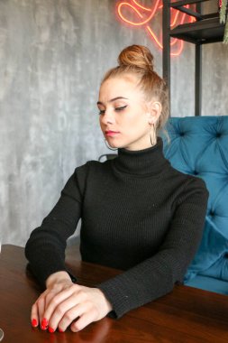 Siyah elbise giyen zarif sarışın kız bir kafede dinleniyor. Reklam, moda, ticari tasarım. Siyah elbiseli bir kız. Bir kafede güzel bir kız.