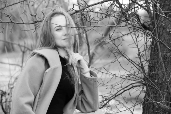 幸せな見事なブロンドの女の子の屋外ライフスタイルのファッションの肖像画 いい笑顔だ 長いライトヘア スタイリッシュなコートを着て 楽しさと陽気な女性 乾燥した葦と湖の近くの自然の風景の上を歩く 黒と白 — ストック写真