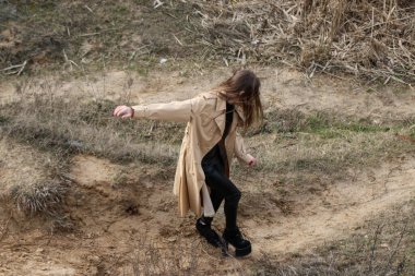 Açık havada mutlu, çarpıcı sarışın kızın moda portresi. Güzel gülümseme. Uzun açık renk saçlı. Şık bir ceket giyiyor. Neşeli ve neşeli bir kadın. Doğal bir arazide, kuru bir sazlığa ve göle yakın yürümek.