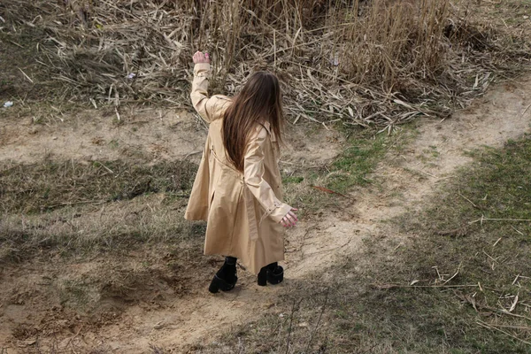 Outdoors lifestyle fashion portrait of happy stunning blonde girl. Beautiful smile. Long light hair. Wearing stylish coat. Joyful and cheerful woman. walk on a natural landscape, near a dry reed and a lake