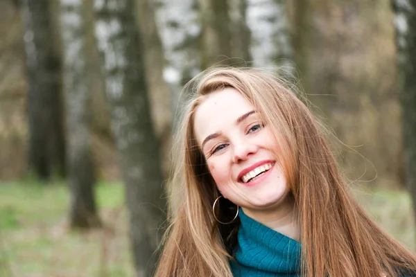 Schönes Mädchen, blond mit langen Haaren, spaziert im Frühling in der Nähe des Waldes im braunen Mantel — Stockfoto