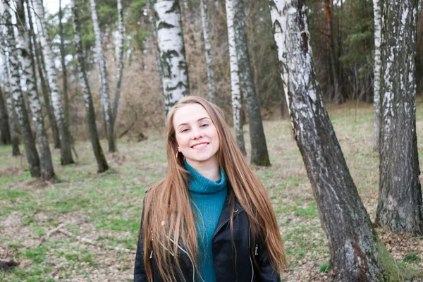 Schönes Mädchen, blond mit langen Haaren, spaziert im Frühling in der Nähe des Waldes im braunen Mantel — Stockfoto