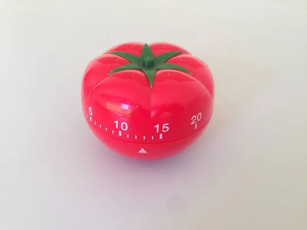 Pomodoro Timer rot mit grünen Details. Tomate auf dem Tisch. lebendige, vieleckige Farben. — Stockfoto