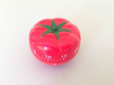 Yeşil detaylarla Pomodoro Zamanlayıcısı kırmızısı. Masada domates var. Canlı, çok açılı renkler.