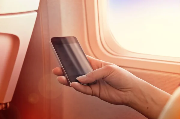 Χρησιμοποιώντας το κινητό σε ένα αεροπλάνο. Smartphone στο χέρι γυναίκα — Φωτογραφία Αρχείου