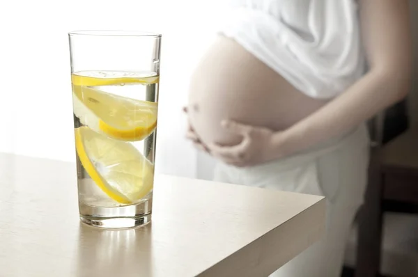 Стакан воды и беременная женщина — стоковое фото