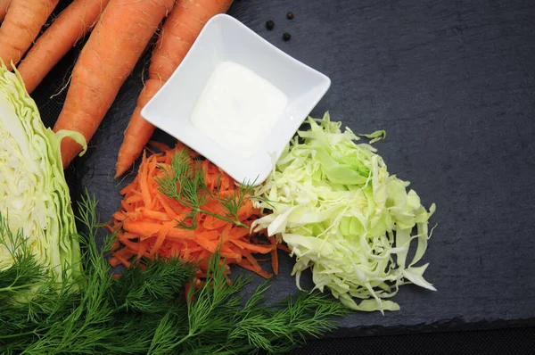 Coleslaw ingredients on black - carrots, cabbage, mayonaise, dill