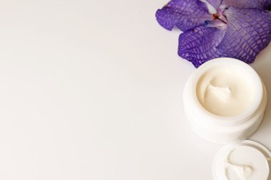 Natürmort krem kavanoz ve beyaz arka plan üzerinde çiçek.