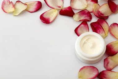 Natürmort krem kavanoz ve beyaz zemin üzerine gül yaprakları ile. 