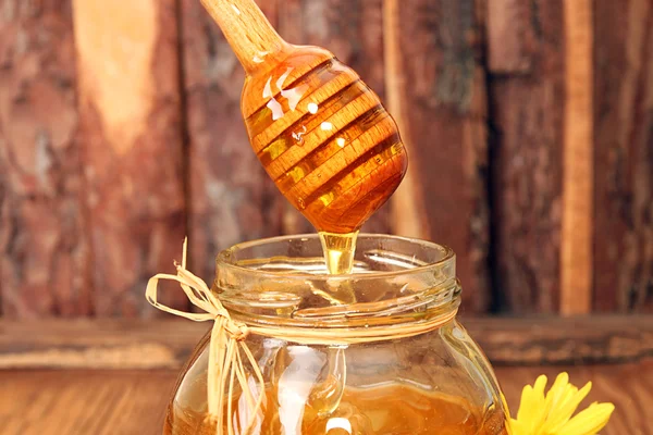 Zoete honing ouderwetse stroomt beneden in glazen pot. — Stockfoto