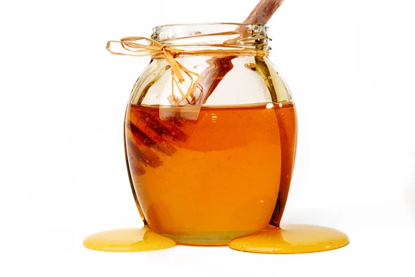 Honey and dipper in jar on white background. — Stock Photo, Image