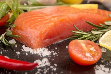 Somon fileto, biber peper, limon dilimi ve siyah üzerinde domates
