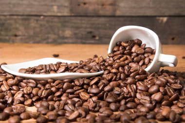 Boş Kupası ve fincan tabağı yığın üzerinde kavrulmuş kahve çekirdekleri.