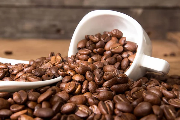 Boş Kupası ve fincan tabağı yığın üzerinde kavrulmuş kahve çekirdekleri.