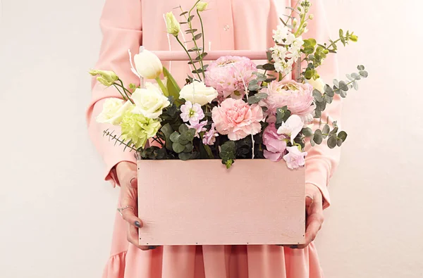 Pink wooden box with flowers roses and carnations in girl's hand