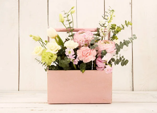 Caixa de madeira rosa com flores rosas e cravos na mão da menina — Fotografia de Stock