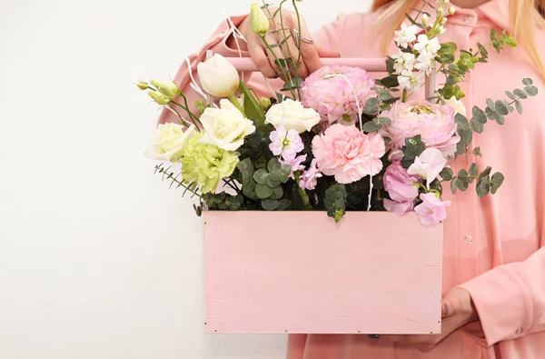 Caixa de madeira rosa com flores rosas e cravos na mão da menina — Fotografia de Stock