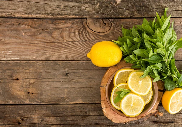 Bundle of mint and slices of lemon on old wooden background. Cop — Stock Photo, Image